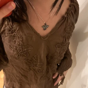 topp från humana - Brun tröja/blus med underbara ”tryck”, lite stor på mig dock, den är lite skrynklig men inget ett strykjärn kan fixa, köpt på humana, används sällan🥰