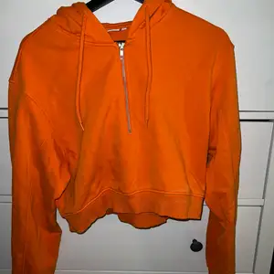 En orange croppad hoodie från Weekday. Köpt för ca 2 år sedan och sparsamt använd. Snygg detalj med dragkedja i fram. 