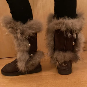 UGG boots med riktig päls  - Bruna UGGs med riktig päls och fina knappar för detaljer. Använda men i rätt bra skick med fluffig päls. 