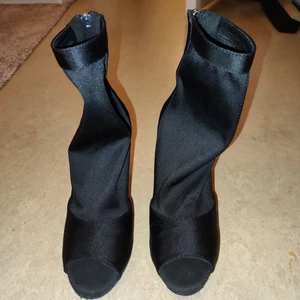 Klackskor 10 cm - Svarta klackskor i strumpmodell med öppen tå. Strl 37. Helt oanvända, har bara testat dem på hemma men kan ej ha dem då klacken är för hög för mig. 10 cm klack. 500 kr nypris.