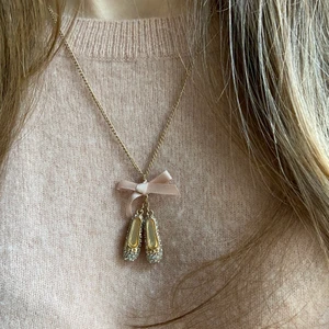 Halsband med ballerinaskor - Supersött halsband med två ballerinaskor och en rosett i guld och rosa. Ballerinaskorna har små vita stenar på sig vilket ger dom ett fint skimmer i ljuset. Kedjan är justerbar i längden. Då själva hänget är avtagbart ger det även möjligheten att byta till en annan kedja om så önskas. Halsbandet i ett mycket bra skick. Ha det till en rosa topp eller en blus till allt ifrån en middag, drink eller skolan. Mitt pris 80kr. GRATIS frakt då det skickas i ett vanligt kuvert!!