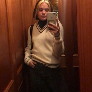 Beige stickad tröja  - Stickad v-ringad tröja, ljust beige med svarta/marinblå detaljer. Köpt på stadsmissionen, står ingen storlek i men skulle tippa på en oversized S/M