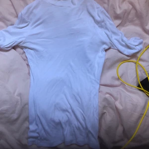 Vit tröja - Vit småribbad tröja med en liten krage och den är kort i ärmarna. själv tycker jag den är väldigt fin men tyvärr kommer den inte till användning.