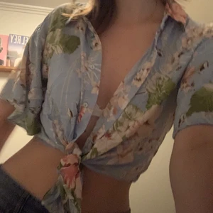 hawaii blus - blå tröja  med blommor och annat. det finns knappar och man kan ha den med ett vitt linne under