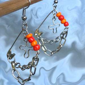 Unika örhängen gjorda med en säkerhetsnål och pärlor i oranget & rött! Coola och färgglada🧡❤️ De är ungefär 4 cm på längden och 3 cm på bredden. Säljer för 50kr + 12kr i frakt!!