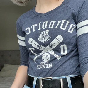 harry potter tröja  - En grå tröja med 3 kvarts armar. Quidditch motiv på framsidan. Inte säker var den kommer ifrån men tror den är från primark i England. Använd men i bra skick 