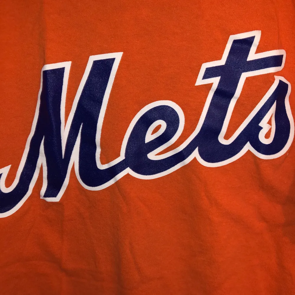 Orange T-Shirt med blått Mets tryck över bröstet. Uppvikta ärmar, den perfekta orangea färgen🧡🔥. T-shirts.