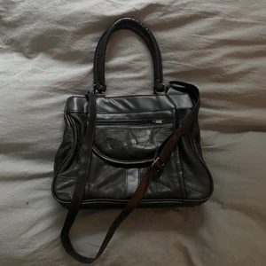 Mörkbrun vintage väska  - Mörkbrun väska i fake läder, köpt secondhand. Finns justerbart axelremsband som även går att ta av. Väskan har även praktiska innerfickor! Har använt väskan en del men den har inga defekter. Säljer då jag har tröttnat på den.