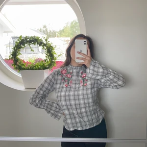 Rutigt blus med lite blommor  - Mjuk blus, med knyting o lite volang på ärmarna 