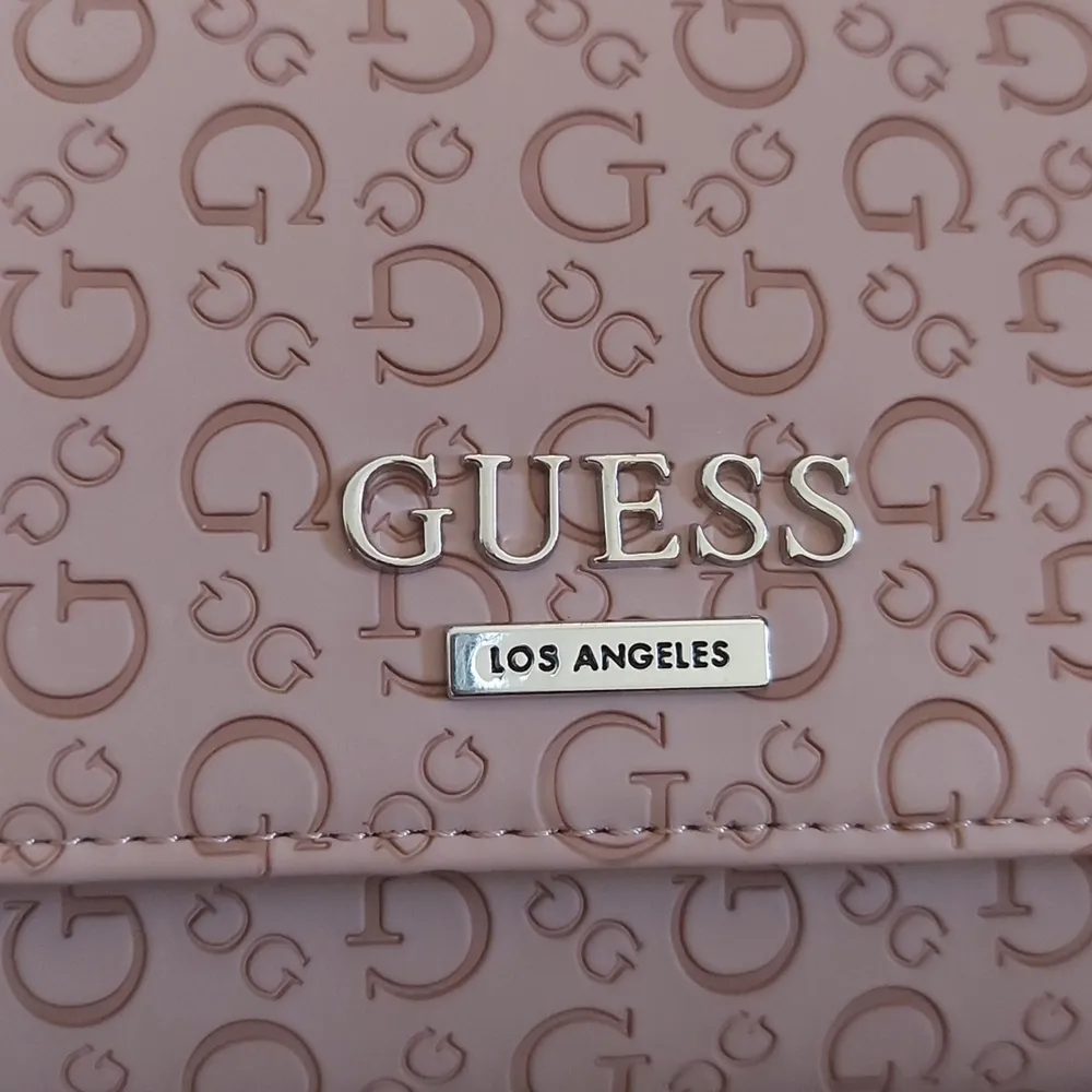 Säljer min helt oanvända Guess Los Angeles handväska i färgen dusty mauve. Handväskan har ficka för mobil och har en massa kort fickor. Storleken är 21 cm i bredd och 11 cm i höjd.. Väskor.