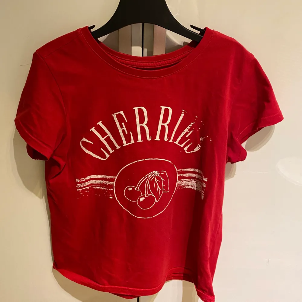 En fin röd t-shirt med körsbärs tryck på framsidan. Mjuk och i bra skick, det ”slitna” i texten är en del av desingnen och ska vara så👍🏻 Frakt tillkommer och jag svarar på frågor🥰 Säljer pga att den är för liten. T-shirts.
