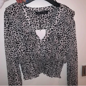 Blus - Säljer denna jätte söta topp från Zara. Vit, svart med leopardmönster och volang framtill. Splitter NY med prislapp kvar! Alltså bara testad. Köpt för 359kr Köpare står för frakt
