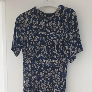 Figurnära blommig klänning - Mörkblå blommig klänning, figurnära och längre bak än fram. Jätteskönt tyg, dragkedja i ryggen.