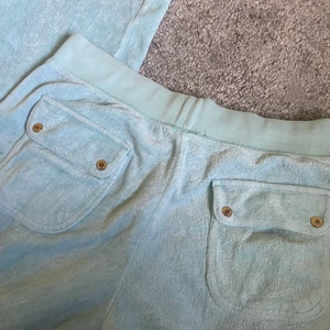 Juicy couture  - Säljer mina super söta mjukisbyxer från juicy couture, dem är köpta för flera år sedan och därav är väldigt använda. Tyget är super fint och har hållt sig bra det är endast paljetterna/diamanterna som har lossnat och även knapparna på rumpan som ser slitna ut! Annars är byxorna i mycket bra skick💗 byxorna är i en superfin mintblå färg (jag har även en matchande ziptröja till om det är ett intresse!)