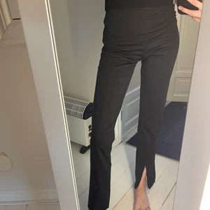 Svarta kostymbyxor - Kostymbyxor i skönt material och dragkedja på sidan. Slits nedtill där man själv kan välja hur stor den ska vara. Är 171 cm för referens 