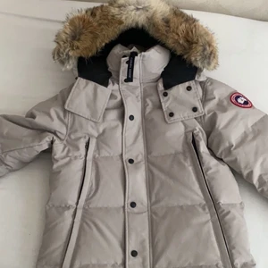 Canada goose storlek S - Säljer en Canada Goose herr jacka, det är en beige wyndham parka i stl S. Jackan är använd under en vinter i någon enstaka månad, den är helt i nyskick och har inga anmärkningar.  Med jackan kommer canada goose boxen, canada goose väska, galje och kvitto m.m   Vill du ha bild på kvittot eller mer på jackan skriv pm.  Nypris är 11200kr, Säljes för 6000