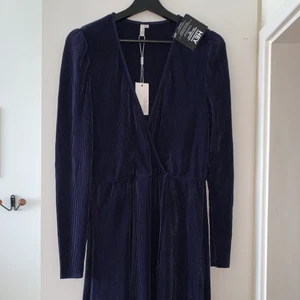 KLÄNNING NELLY - Superfin plisserad marinblå omlottklänning från Nelly. Helt ny med prislapp kvar.