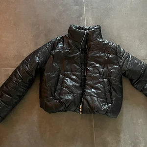 Svart pufferjacka i glänsigt material - Svart pufferjacka i glänsigt material. Köpt för 2 år sedan från märket Rising i storlek 38, passar även 36. Bara använd ett fåtal gånger🥰🥰