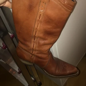 Cowboy boots - Äkta läder Cowboyboots! Storlek 39. Köptes i somras. Jättefint skick. Har smörjt in dem. I en konjaksbrun färg. Vet inte hur mkt dem kostar att skicka men dem är inte super, supertunga. Frakten kommer hamna mellan 50-100kr iallafall.  Dem här skorna passar skitbra till den bruna, långa skinnjackan jag säljer! 