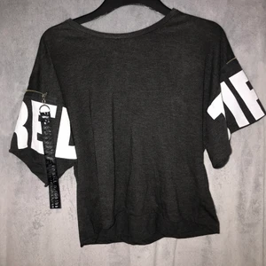 River island - Jättefin baggy t-shirt. armarna är baggy med detalj. Grå färg med vita detaljer på armen samt en kedja detalj. Använt fåtal gånger.S/M