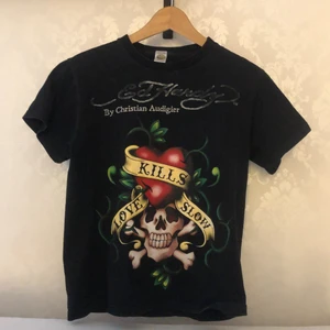 Ed Hardy tisha  - Säljer min kära Ed Hardy tisha som tyvärr aldrig blivit använd. Jag uppskattar storleken till en M, den är i bästa möjliga skick och är äkta. Pris är diskuterbart! Kontakta mig vid frågor eller fler bilder🤝❤️‍🔥 Möter upp i centrala Uppsala eller skickar mot fraktkostnad😎