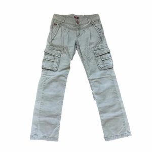 Lågmidjade cargo byxor - Säljer dessa lågmidjade cargo byxor som ger en lite 2000s vibe. Färgen är typ greige och dessa sitter superfint på! Superbra condition på dessa även fast de är rätt gamla då jag fick de av min mamma. Tycker själv de är superfina, men kommer inte till mycket användning och är lite för små. Passar bra på storlek 36/34/S