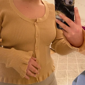 Kofta från asos design - Beige/ljusbrun kofta från asos i storlek 42. Jättefina volang detaljer vid ärmarna och längst ner🤩 Använd en gång säljer pga att jag inte använt mer. Storlek 42 men är väldigt stretchig och kan passa även om man har strl 40 eller 44 