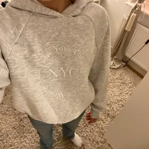 En jättefin och oanvänd grå hoodie med vit text på.
