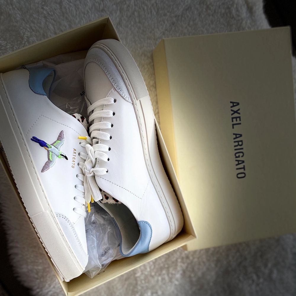 Oanvänd sneakers ”Axel Arigato ”, vit sneaker med övre läder.Prislapp på ,ingår även en väska till skorna.. Skor.