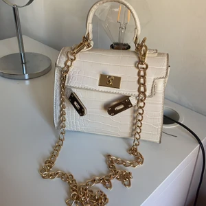 Väska - Säljer en super fin o praktisk väska i vit o guld färg från Gina tricot. Jätte fin mönstring, har aldrig använt. Säljs för 350 