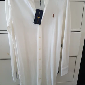 Ralph  Lauren  vit skjortklänning  - Ny aldrig använd bara testad. Prislapp är kvar// äkta// fick den som present men passar tyvärr inte mig. Träffade smink när jag skulle prova den kolla  bilder! men inget  som störr det går säkert att bort tvättar det !därav  priset . Är öppen för byte 😊