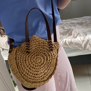 Fin väska i strå  - Fin väska i ”strå”. Har axelband men även kortare band som man kan hålla i. Kan stängas med ett snöre. Har bruna och guldiga detaljer. Passar fint till en sommaroutfit. ☺️🧡☀️💗 Aldrig använd och är i nyskick. Ingen koll på vilka mått den är i men gissa på ca 20x20 cm. 