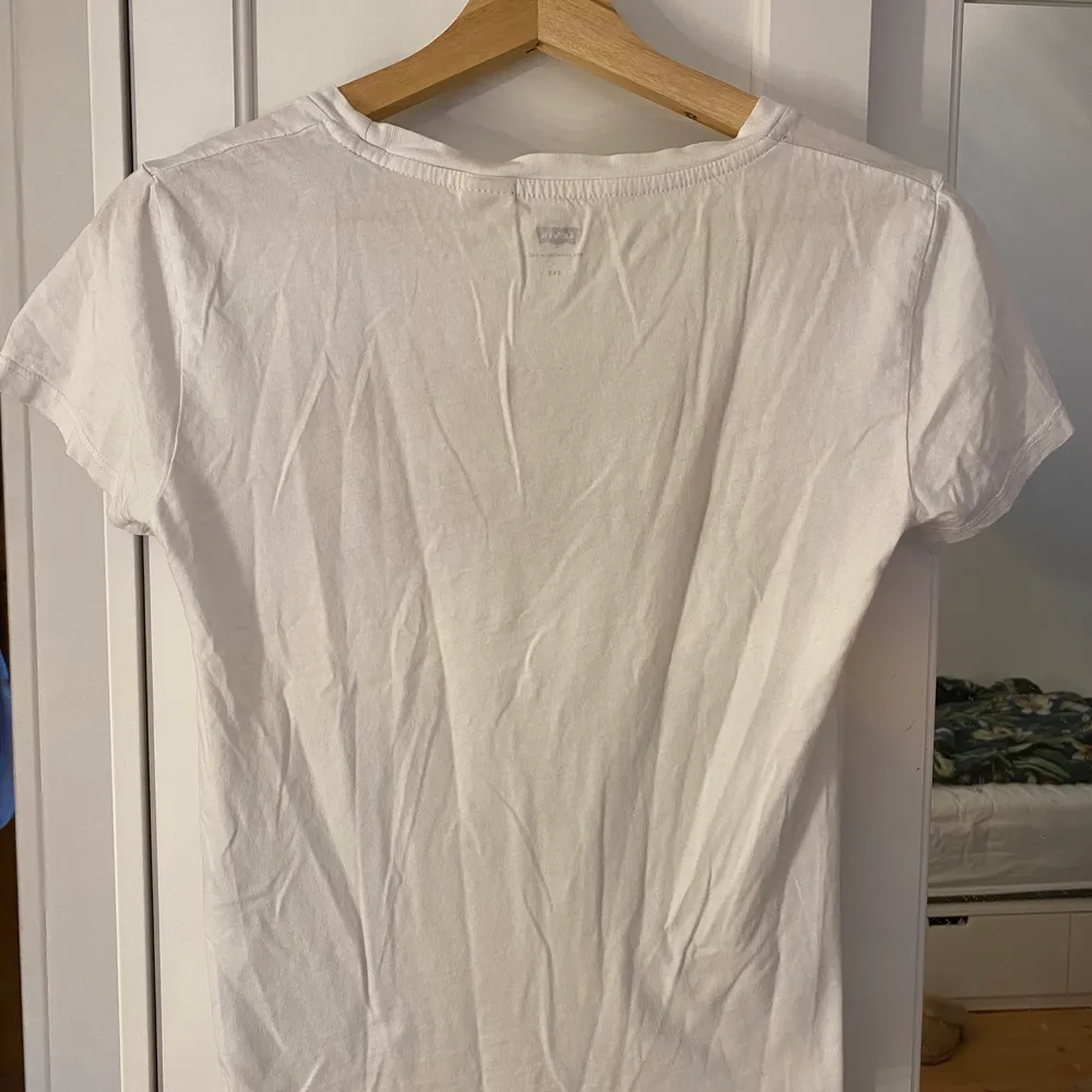 En fin o klassisk Levi's t-shirt. Väldigt bra skick, inga gula fläckar som ibland förekommer på vita t-shirts men inga här på. Storlek XXS.. Toppar.