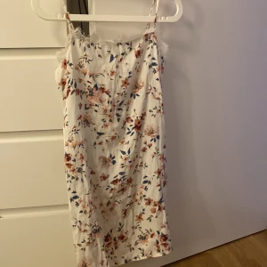 Slipklänning - En jättefin slipklänning i satinmaterial. Superskön att ha en varm dag om man ska till en badplats! Fint blommönster och en fin spets kant upptill!