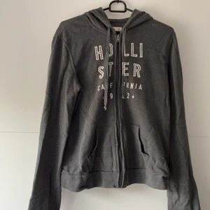 Hollister luvtröja - Grå luvtröja från Hollister med text broderat i vitt. Väldigt mjuk och skön! Kan mötas upp i Nyköping/Göteborg eller posta men då står kund för frakt 🌼