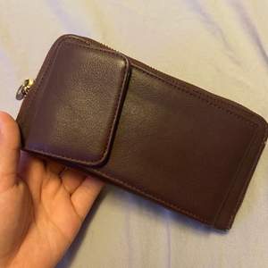 En plånbok med telefon hållare, aldrig använd i fint skick. Kommer även med ett snöre att kunna hålla den med.