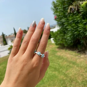 en ljusblå pärlring  - Tre vita pärlor och sen en blå blomma hela ringen runt