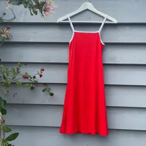 Röd klänning med vita detaljer. Väldigt skönt tyg, stretchig och dessutom luftig. Perfekt en varm sommardag! Frakt tillkommer