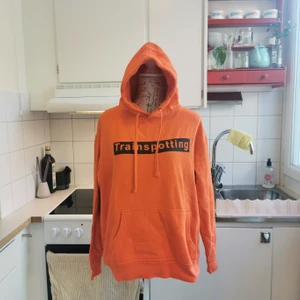 Cool hoodie köpt i London, Trainspotting, M - Cool alternativ hoodie som jag köpt under av mina turer till London, använd ca 2-3ggr och sedan gömts i garderoben. Hoodien är lysande orange med svart tryck och citat från kultklassikern Trainspotting från -96, ett läckert plagg i en alternativ garderob 🖤