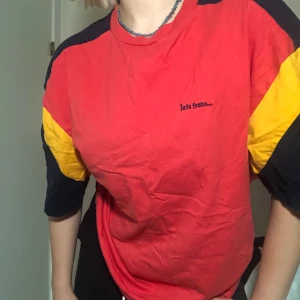 Orange, gul och mörkblå t-shirt - T-shirt från Urban Outfitters i oversized modell. Tryck där de står ”iets frans...”. Mycket bra skick. 