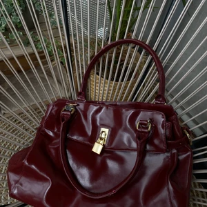 Trendig handväska! - Röd handväska från Rizzo. Beredd: 40 cm. Höjd: 25. Djup: 10 cm. Priset är nedsatt pågrund av defekter/slitningar på ”remen” (se bild). 