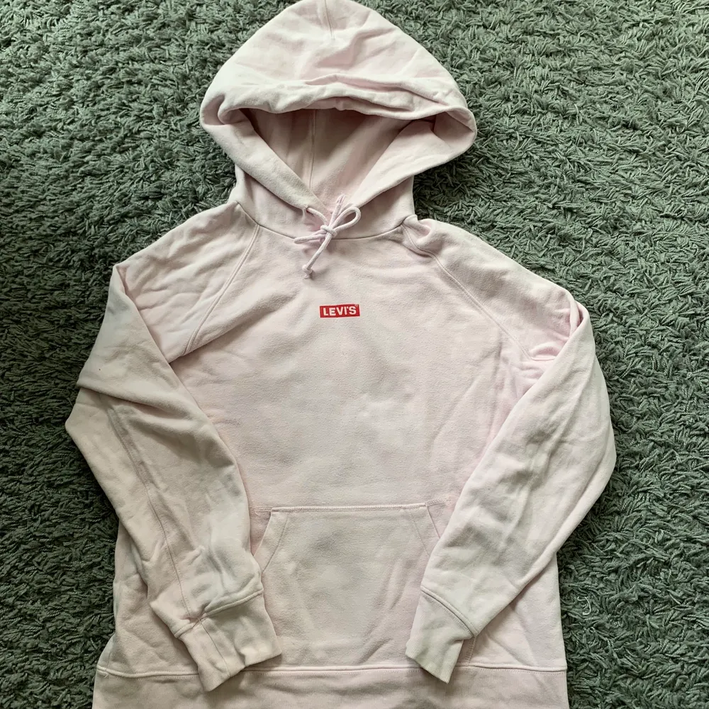 Säljer en ljusrosa Levis hoodie som inte kommer till användning. Andra bilden beskriver färgen bäst💗 På sista bilden kan ni se att knuten på snöret har gått upp så att det är lite spretigt✨ Pris kan diskuteras, NYPRIS: 800kr. Hoodies.