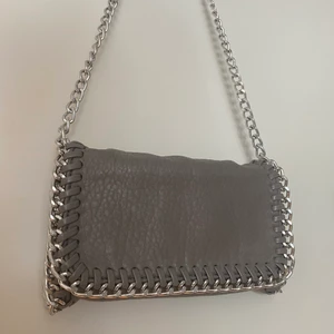 Tiamo pricilla väska - grå - Jättefin tiamo väska som säljs pga att jag har för många väskor. 3dje bilden visar att färgen försvunnit lite men inget som syns tydligt! Köparen står för frakten (som tillkommer) och betalning sker via swish. Skriv för fler bilder samt frågor.