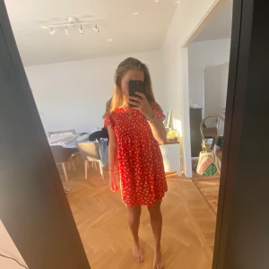 Röd klänning med vita blommor & knappar - Den här så fina klänningen är röd och har små vita blommor på sig, den ska egentligen bäras så att knapparna är framtill men går även att ha som jag har på bilden, perfekt på sommaren, det går bra med leverans men då står köparen för frakten❤️🌸