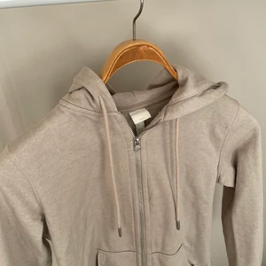 Huvtröja - En huvtröja från hm i en beige/grå färg. Aldrig användt. Passar tajt runt midjan när stängd och när öppen sitter den löst för mig som brukar ha storlek S. Denna är i storlek XS. ❤️ Säljer för 90 kr.