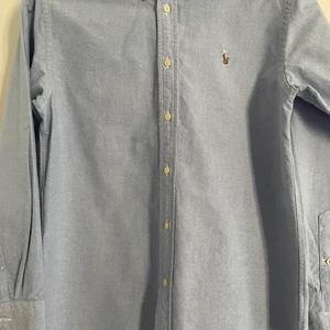 Ljusblå Ralph lauren skjorta, fint skick - Ljusblå skjorta som är köpt på NK i Stockholm, storlek: 16 år, 1000 kr nypris, fint skick och använd fåtal gånger!