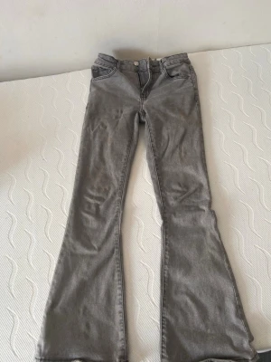 Grå bootcut jeans med hög midja - Säljer ett par gråa bootcut jeans med låg midja. Materialet är denim med en mjuk känsla och lätt stretch. 