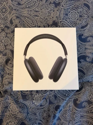 Apple AirPods Max 2 med Smart Case - Snygga och moderna over-ear hörlurar från Apple i svart färg. AirPods Max 2 levereras med Smart Case och har en stilren design med metall och mesh-material för extra komfort. Perfekta för musik, gaming eller film med grym ljudkvalitet.