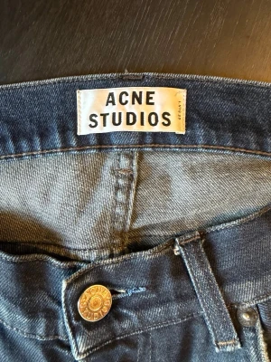 Blå jeans från Acne Studios - Snygga blå jeans från Acne Studios i klassisk femficksmodell. Jeansen har en smal passform och är tillverkade i mjukt denimtyg med lätt tvättad look. Perfekta för dig som gillar stilrena och trendiga basplagg. Den har lagningar och slitningar som syns på bilderna.