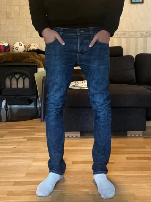 Nudie Jeans Grim Tim - Säljer dessa sjukt snygga jeansen från Nudie i den populära modellen Grim Tim. Färgen heter Dry Open Navy. De är i superbra skick och i storlek 31/32 men lite små i storleken. Personen på bilden är 180 cm och väger 67 kg. 